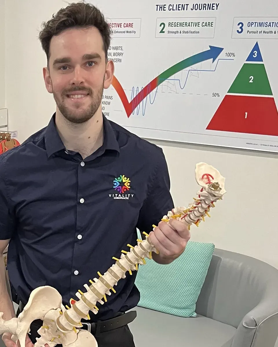 Dr James Stout (Chiropractor) holding a spine model at Vitality Chiropractic, Yokine